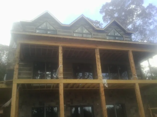 Dormers and porch framing on a large log home under construction — Roof Coating work by our crew in Grand Forks Afb
