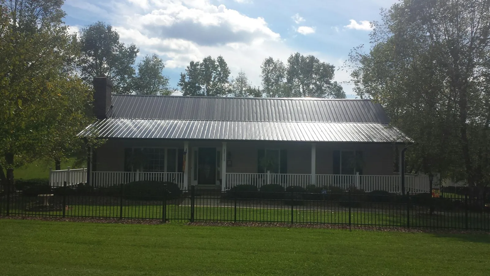 Gray metal roof on a brick ranch with a full width front porch — Gutter Guard Installation work by our crew in Grand Forks Afb