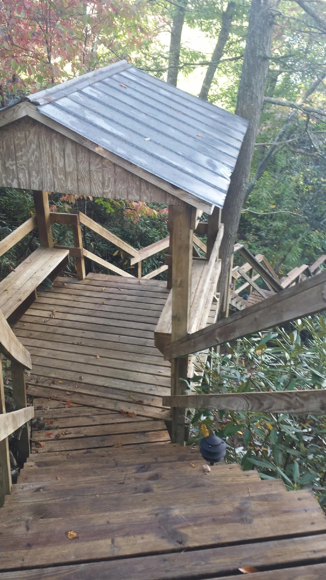 Metal roofed shelter over wooden steps on a wooded walkway — Skylight Repair & Installation work by our crew in Grand Forks Afb