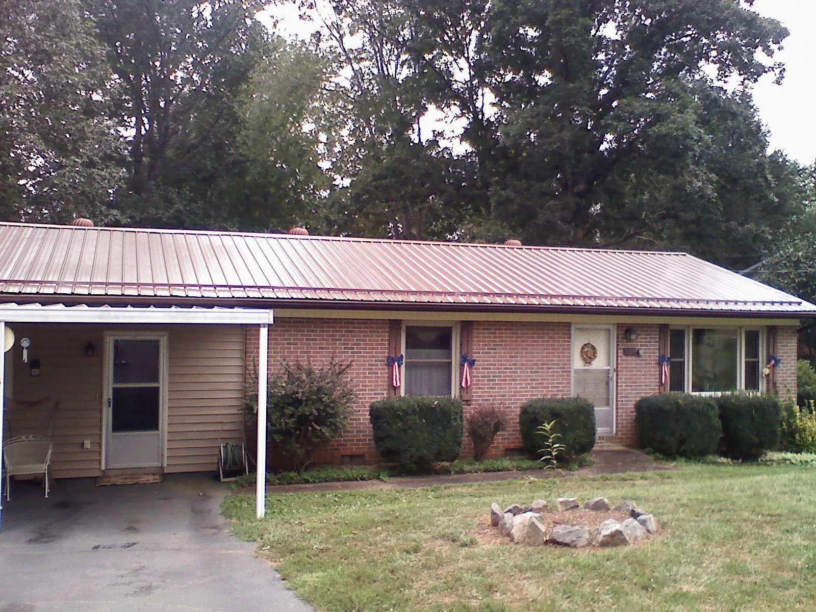 Bronze metal roof and carport on a brick ranch home — Roof Repair work by our crew in Grand Forks Afb