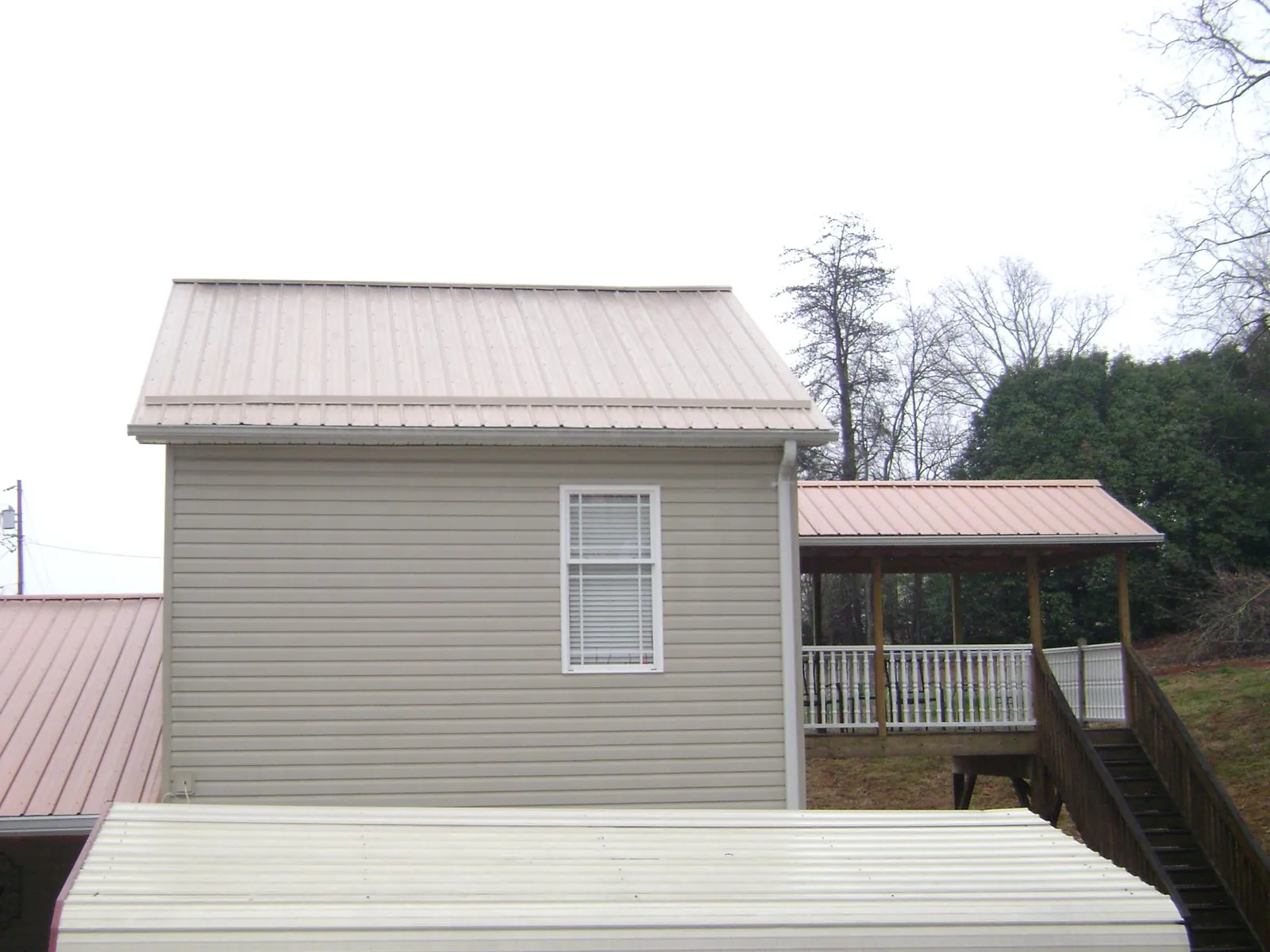 Tan metal roofs on a two story addition and attached porch, from a Roof Replacement job in Grand Forks Afb