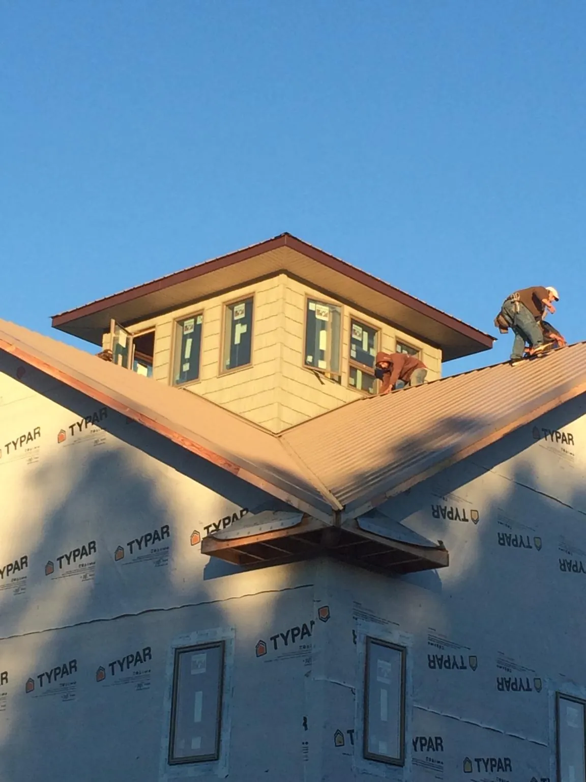 Roofers working around a rooftop cupola on a new metal roof at sunset — Roof Waterproofing in Grand Forks Afb by Roofing Brothers